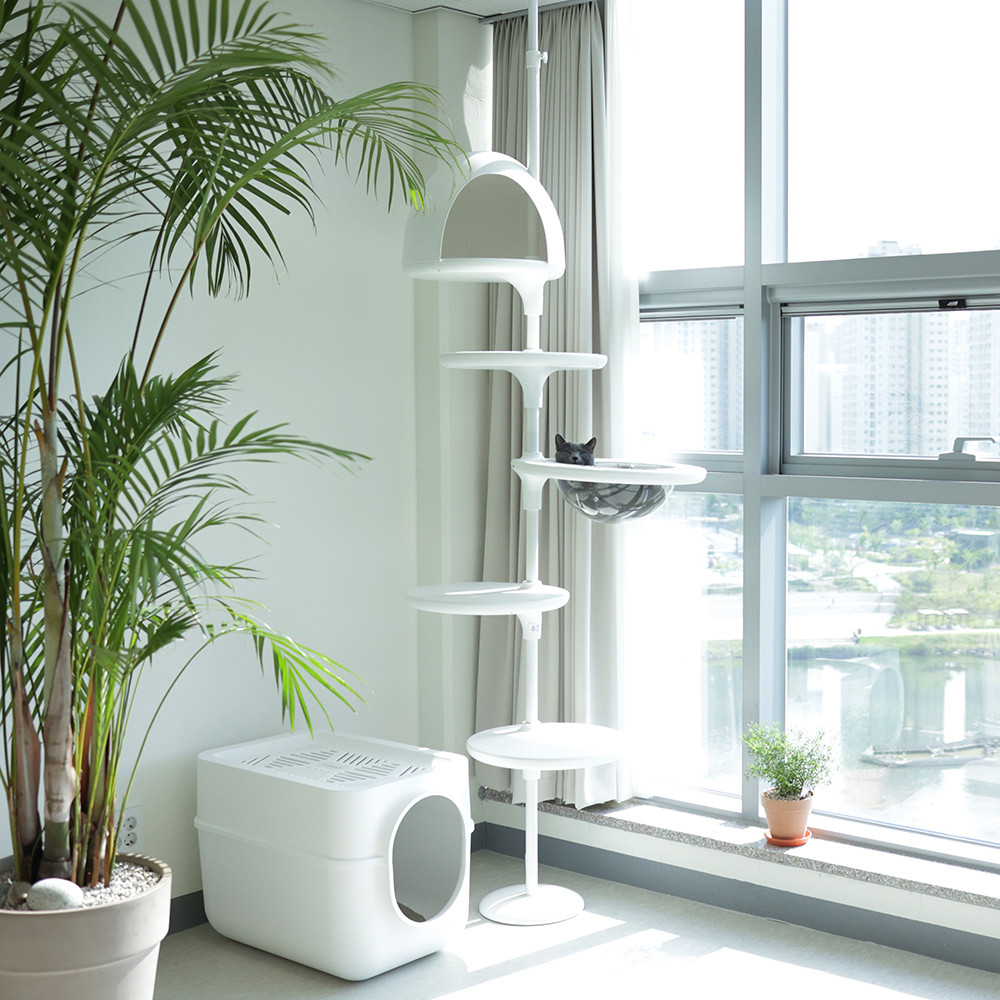 Freestanding modern cat tower beside a large apartment window